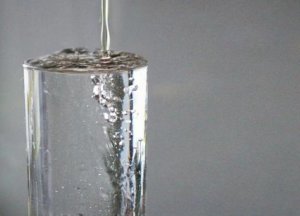 トリクルダウンを象徴するコップから溢れる水のイメージ写真
